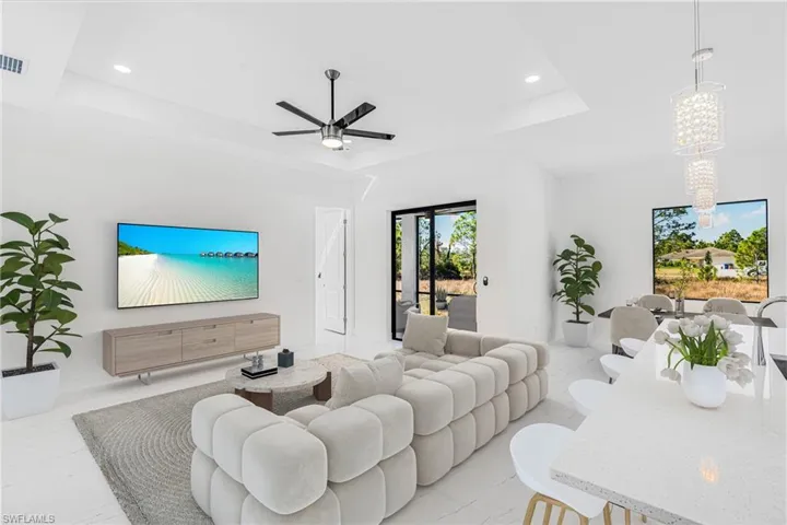 Living room with a raised ceiling, recessed lighting, and a ceiling fan