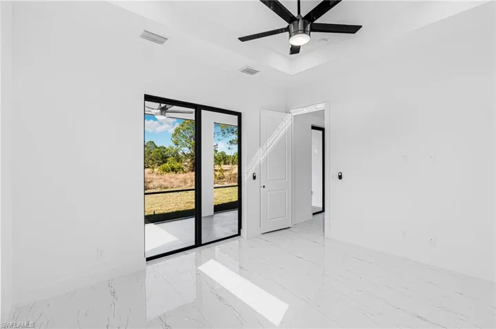 Spare room with light marble finish flooring, a ceiling fan, and a tray ceiling