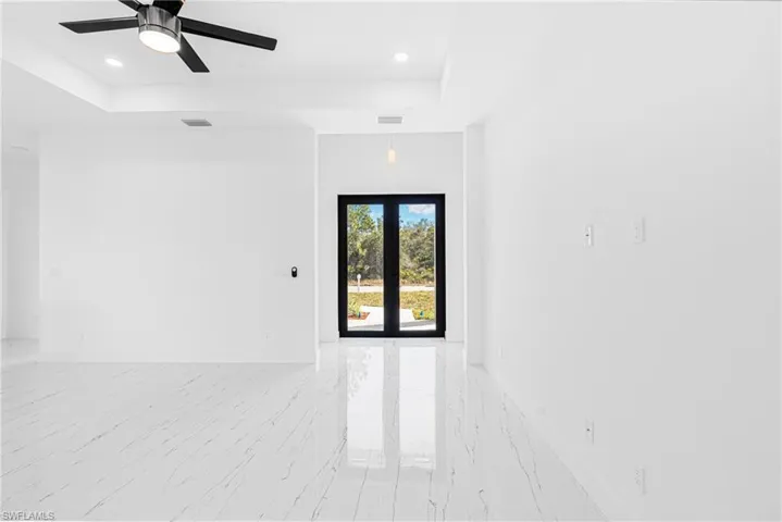 Unfurnished room with a raised ceiling, light marble finish flooring, ceiling fan, and recessed lighting
