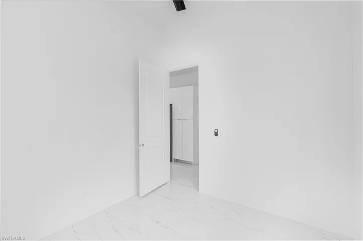 Unfurnished room featuring light marble finish floors and baseboards