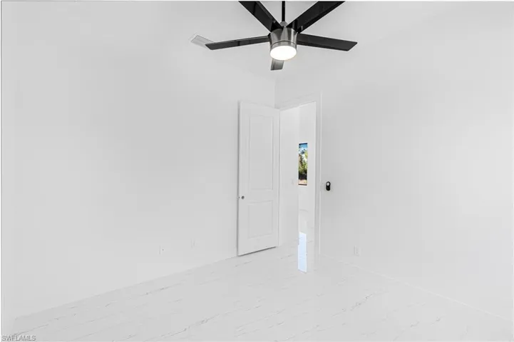 Empty room with light marble finish floors and a ceiling fan