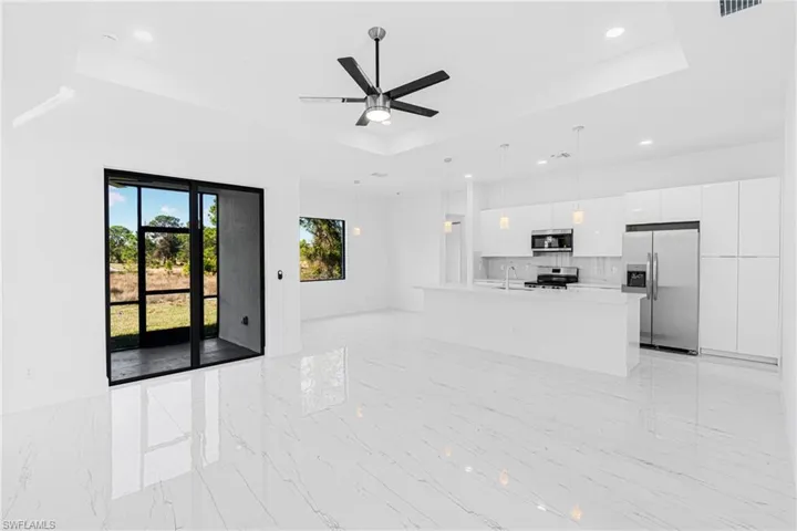 Unfurnished living room featuring a raised ceiling, ceiling fan, recessed lighting, and light marble finish flooring