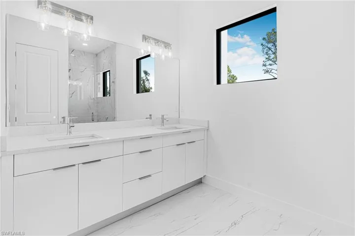 Full bathroom featuring marble finish flooring, a marble finish shower, and double vanity