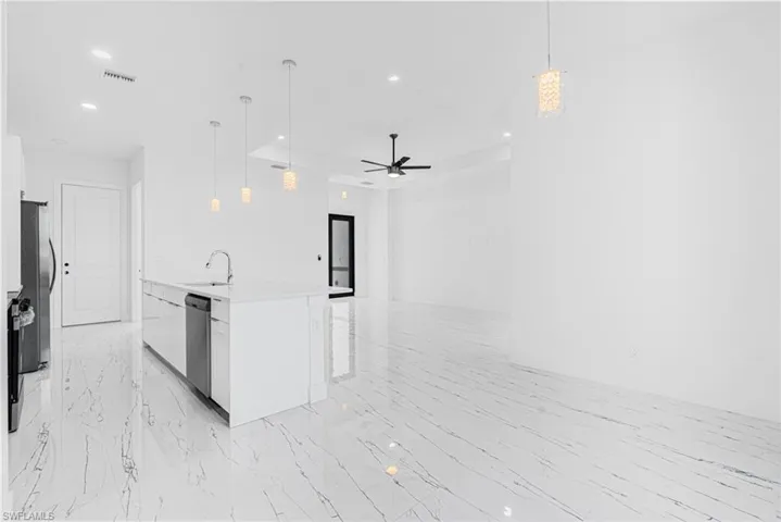 Kitchen featuring open floor plan, light countertops, white cabinets, recessed lighting, and pendant lighting