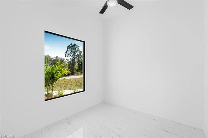 Spare room featuring light marble finish floors and ceiling fan
