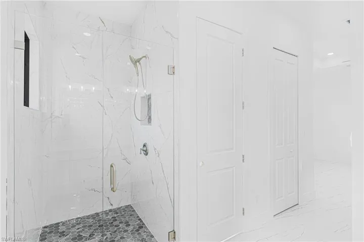 Bathroom with a marble finish shower, marble look tile flooring, a closet, and recessed lighting