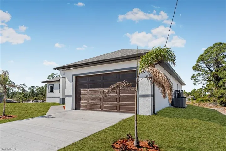 View of property exterior featuring stucco siding, driveway, an attached garage, and a lawn