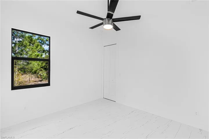 Empty room with light marble finish floors and ceiling fan