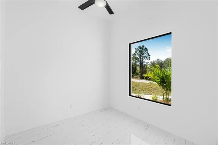 Unfurnished room featuring light marble finish flooring and ceiling fan