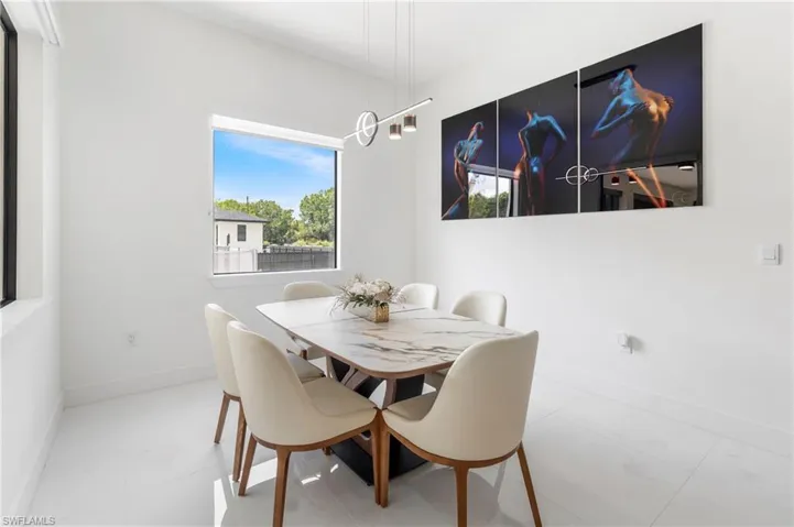 Dining area featuring white walls, large windows, and contemporary pendant lighting