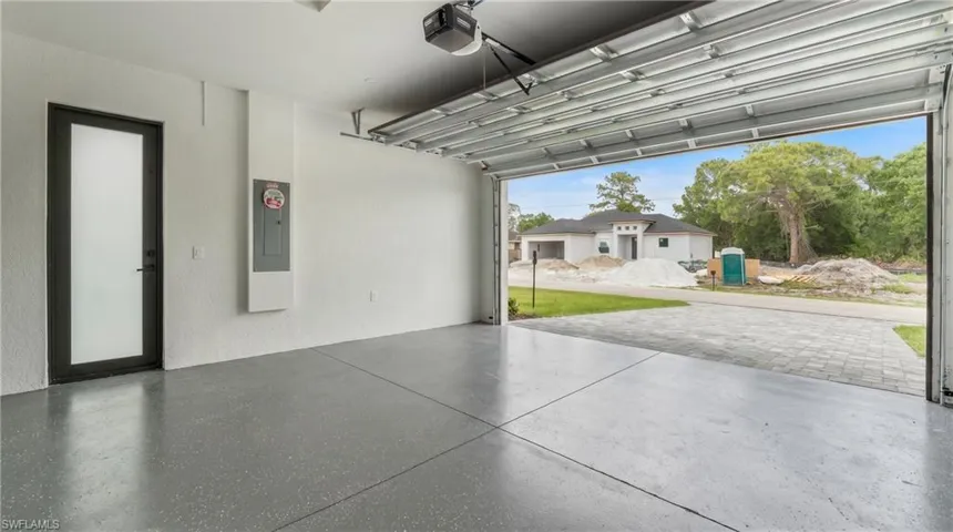 Spacious garage featuring epoxy flooring, a modern frosted glass door, and a full-view garage door