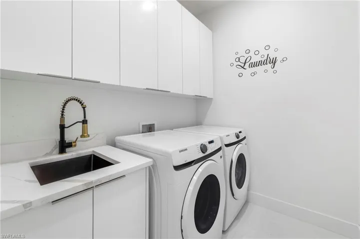 Utility room featuring white cabinetry, a black sink with a coil spring faucet, a light-toned countertop, and light-toned flooring