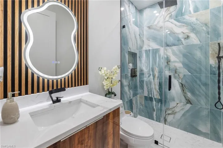 Bathroom featuring a large walk-in shower with patterned blue and white tiles, a glass enclosure, and a built-in niche