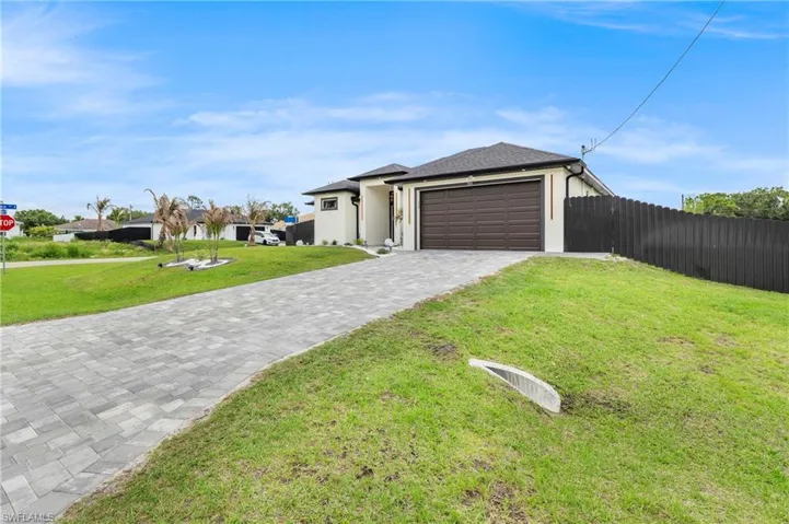 Contemporary exterior featuring a paver driveway, dark brown garage door, and a dark privacy fence
