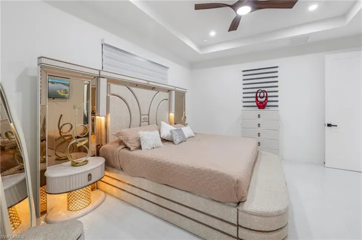 Spacious bedroom featuring clean white walls and a contemporary ceiling fan