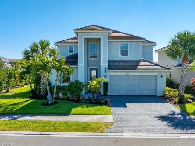View of front of property featuring decorative driveway, a tile roof, an attached garage, a front yard, and stucco siding