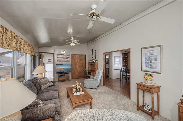 Living area featuring high ceilings, dual ceiling fans, carpeted flooring, and built-in wood-finish closet doors