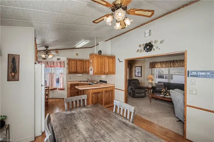 Kitchen featuring wood cabinetry, a breakfast bar, and wood-finish flooring, complemented by overhead ceiling fan lighting