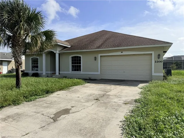 Single-story residence featuring a concrete driveway, two-car garage, arched entryway with structural columns, and arched window detailing