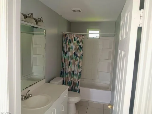 Full bathroom featuring light tile patterned flooring, vanity, and shower / tub combo with curtain