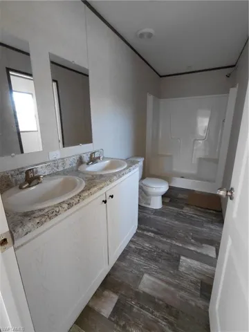Bathroom with double vanity, dark wood finished floors, and washtub / shower combination