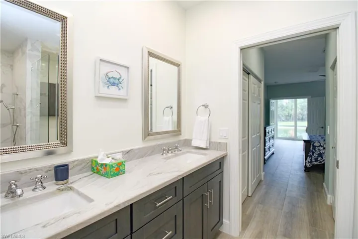 Bathroom featuring a shower with door, double sink vanity, and hardwood / wood-style floors