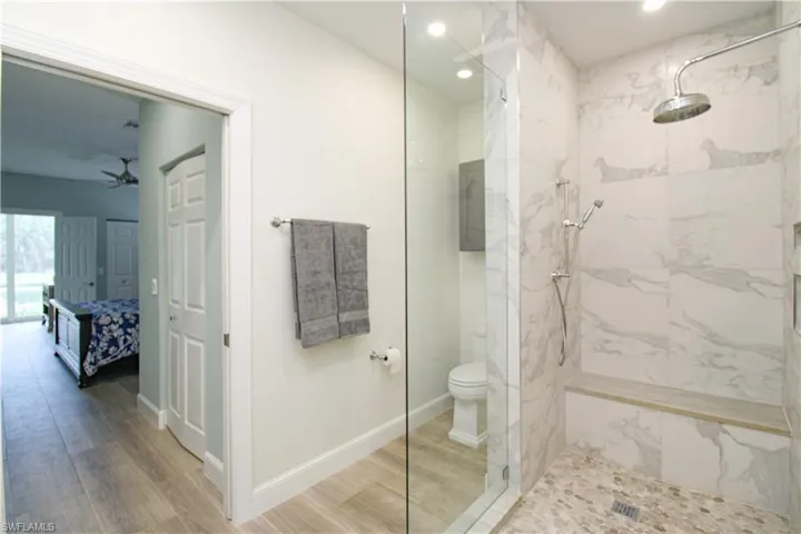 Bathroom featuring ceiling fan, hardwood / wood-style floors, an enclosed shower, and toilet