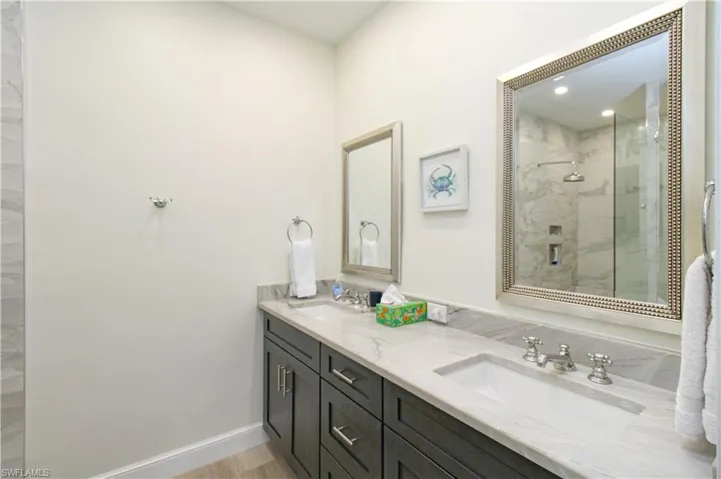 Bathroom featuring a shower with door and double sink vanity
