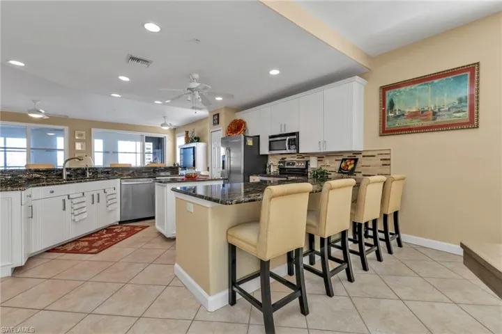 Kitchen featuring white cabinets, a kitchen breakfast bar, stainless steel appliances, and dark stone counters