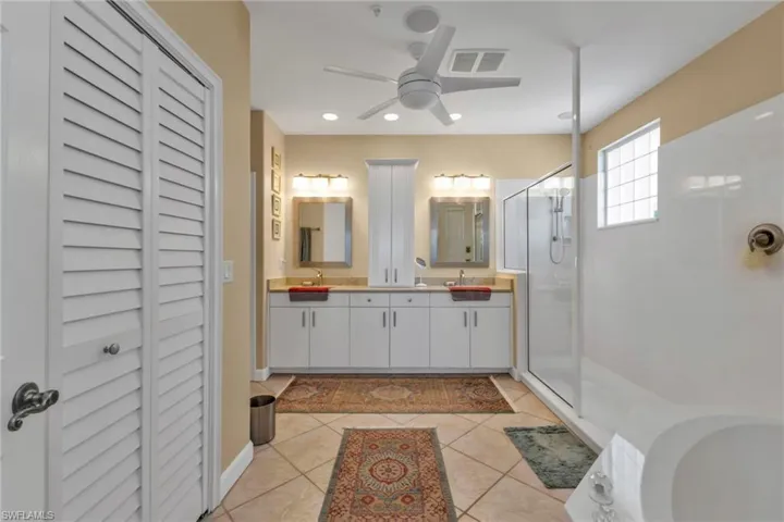 Bathroom featuring vanity, tile patterned floors, a shower with door, and ceiling fan