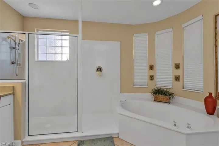 Bathroom with tile patterned floors, vanity, and plus walk in shower