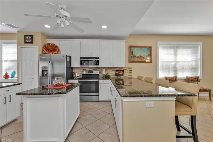 Kitchen featuring a center island, a breakfast bar area, light tile patterned floors, tasteful backsplash, and stainless steel appliances