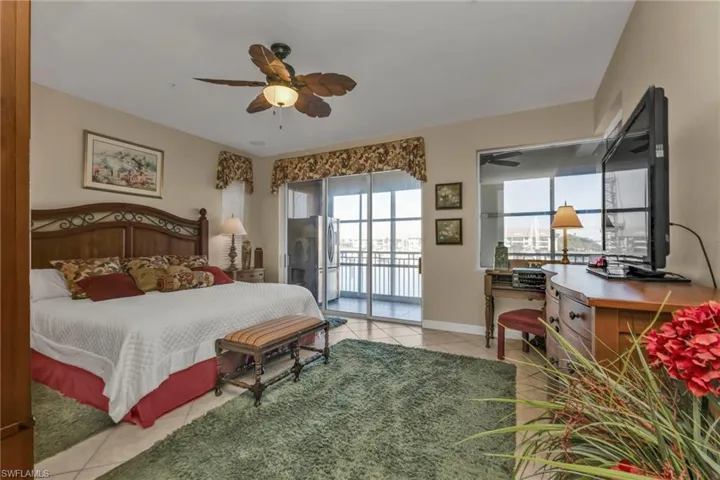 Bedroom with ceiling fan, light tile patterned floors, and access to outside