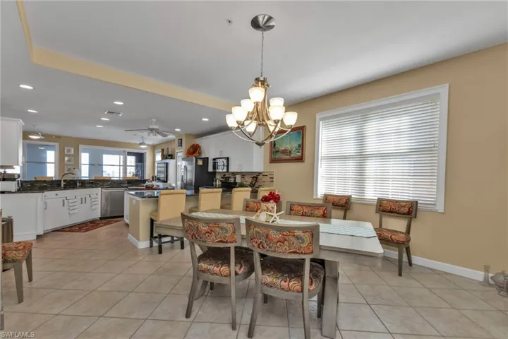 Tiled dining space with ceiling fan with notable chandelier and sink