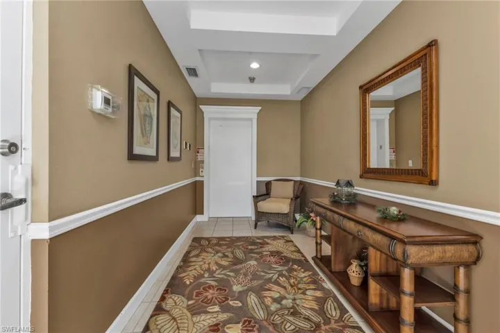 Corridor featuring light tile patterned flooring and a tray ceiling