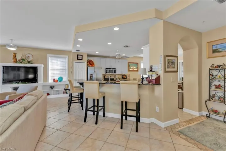 Kitchen featuring kitchen peninsula, appliances with stainless steel finishes, a kitchen breakfast bar, ceiling fan, and white cabinets