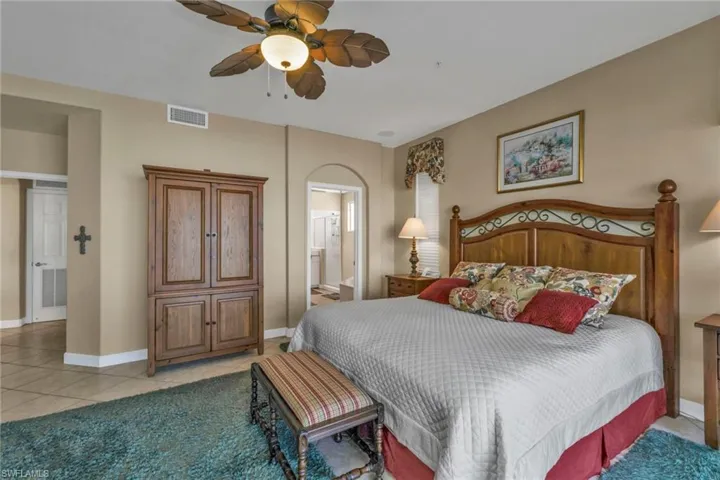 Bedroom with connected bathroom, ceiling fan, and light tile patterned floors