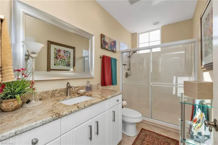 Bathroom featuring tile patterned floors, vanity, toilet, and an enclosed shower