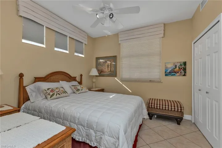 Bedroom with ceiling fan, a closet, and light tile patterned floors