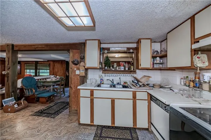 Kitchen featuring open shelves, light countertops, a textured ceiling, white appliances, and light flooring