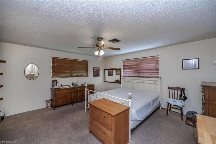 Bedroom with carpet, ceiling fan, and a textured ceiling