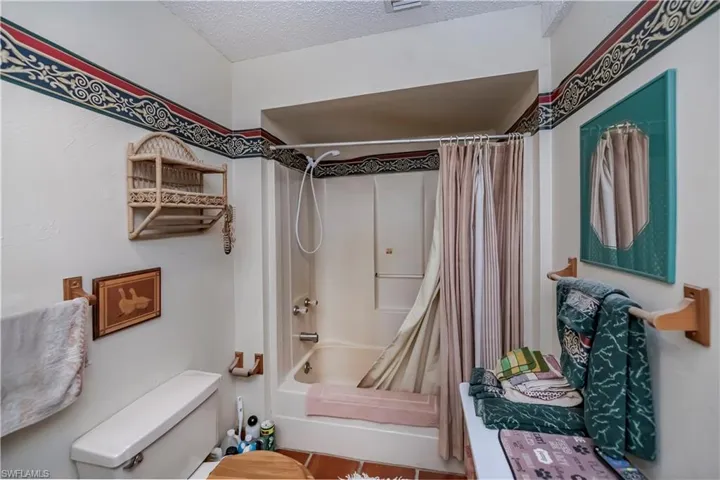Full bathroom featuring shower / bath combo with shower curtain and a textured ceiling