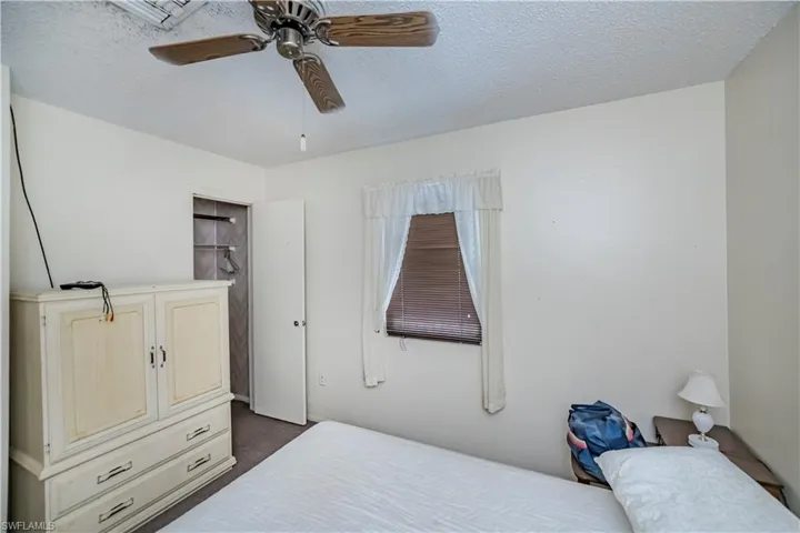 Bedroom featuring dark colored carpet, a textured ceiling, and a ceiling fan