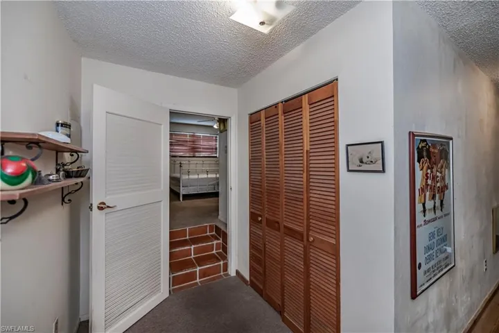 Corridor with a textured ceiling, carpet flooring, and tile patterned flooring