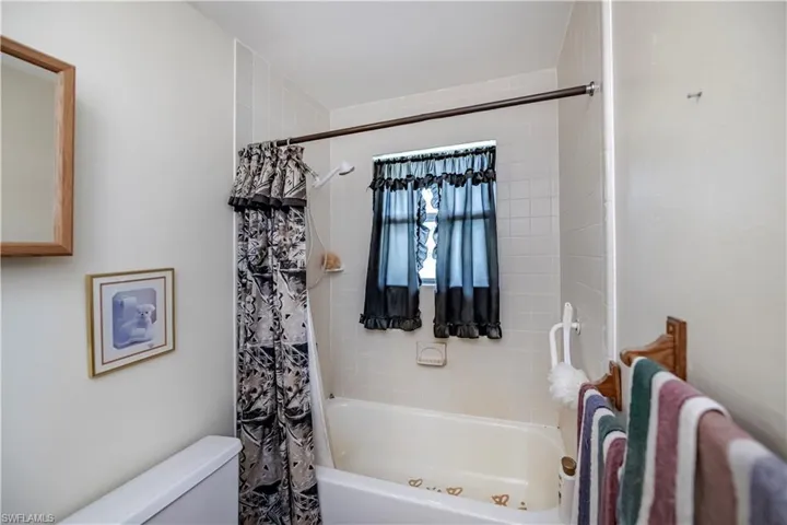 Bathroom featuring toilet and shower / tub combo with curtain
