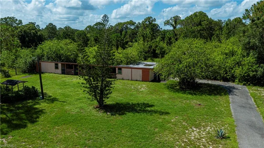 View of green lawn with a wooded view, an outdoor structure, and an outbuilding