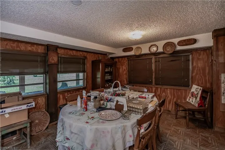 Dining room with a textured ceiling and wood walls