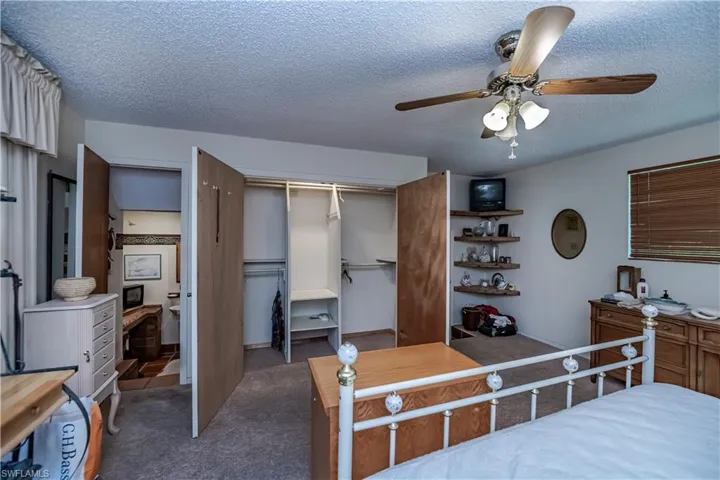 Bedroom with carpet flooring, a closet, a textured ceiling, and a ceiling fan