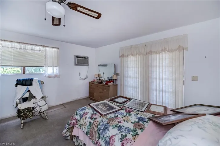 Bedroom featuring carpet flooring, a wall unit AC, and ceiling fan