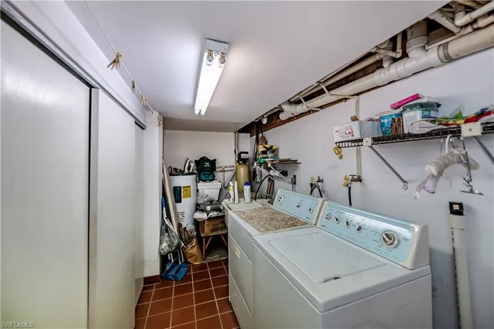 Laundry area featuring washer and clothes dryer, dark tile patterned flooring, and electric water heater
